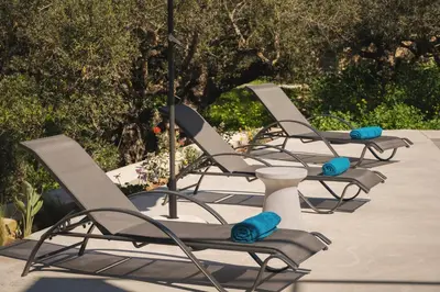 four lounge chairs are lined up in a row at Mythelea Luxury Villa in Kissamos