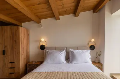 a bedroom with a bed with white sheets and wooden ceilings at Fantasea Villas, villa Lumi in Stérnai