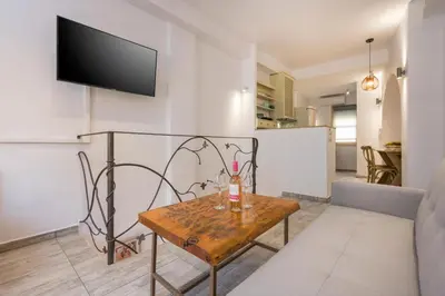 a living room with a table and a tv on a wall at Crescendo Splantzia in Chania Town