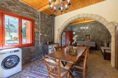 a kitchen and dining room with a table and a washer at Vavouledo Village House in Khamalévri