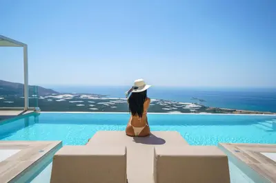 a woman in a bikini sitting on a chair next to a swimming pool at Nafsika Xenia - Odysseus in Falasarna