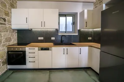 a kitchen with white cabinets and a sink at Nafsika Xenia - Odysseus in Falasarna