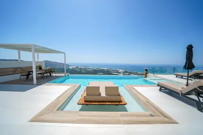 a swimming pool with two lounge chairs and the ocean at Nafsika Xenia - Odysseus in Falasarna