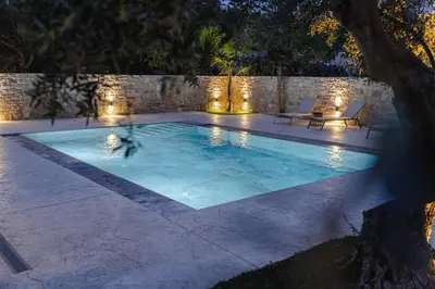 a swimming pool with lights in a backyard at night at Villa Avelios in Karefilianá