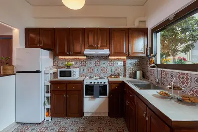 a kitchen with wooden cabinets and a white refrigerator at Katsambas Apartment - Cozy Retro-Luxury with Balcony in Chania Town