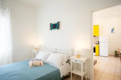 a white bedroom with a bed and a mirror at Bella Apartment in Chania Town