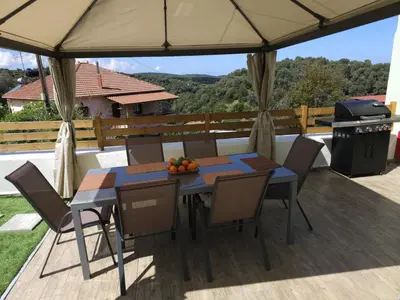 a table and chairs under an umbrella on a deck at Elaida Home in Psathoyiánnos