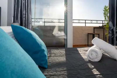 a bedroom with a bed with blue pillows and a window at Be Crete - Horizon in Chania Town