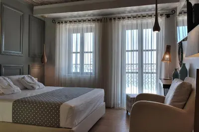 a bedroom with a bed and a chair and windows at Elia Zampeliou Hotel in Chania Town