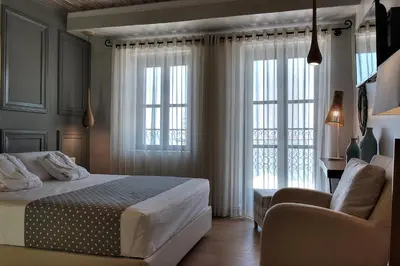 a bedroom with a bed and a chair and windows at Elia Zampeliou Hotel in Chania Town