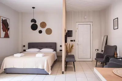 a white bedroom with a bed and a chair at Nektaria Studio in Chania Town