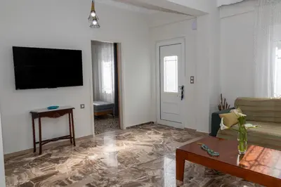 a living room with a couch and a tv on a wall at Lumea Apartment in Chania Town