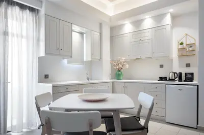 a kitchen with white cabinets and a table and chairs at Forum City Apartments in Chania Town