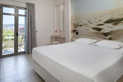 a bedroom with a white bed and a balcony at Forum City Apartments in Chania Town