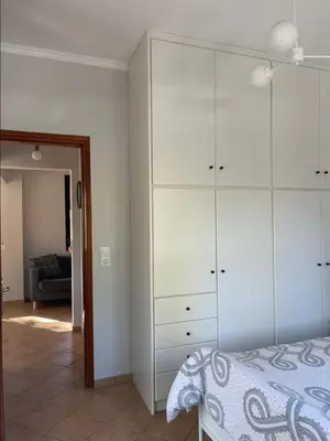 a bedroom with a bed and a large white cabinet at Green door in Nerokoúros