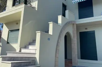 a white house with stairs and an archway at Green door in Nerokoúros