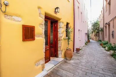 an alley with a yellow building and a red door at Maisonette in center of Chania with roofgarden! in Chania Town