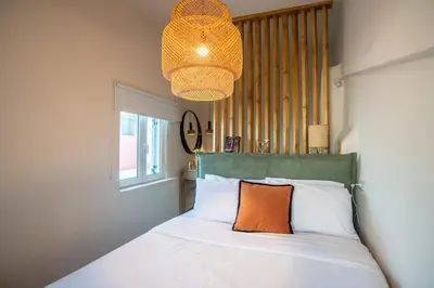 a bedroom with a bed with an orange pillow and a chandelier at Central old Town house with jacuzzi and yard,4ppl in Chania Town