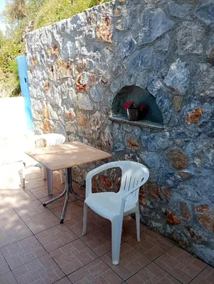 a table and chairs next to a stone wall at Stefanos Garden2 in Arménoi