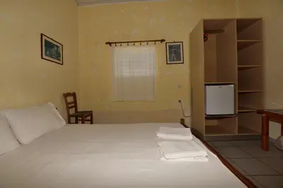 a bedroom with a large white bed and a tv at Anonymous Homestay in Palaiochóra