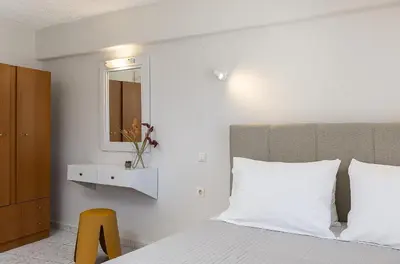a bedroom with a bed with a mirror and a yellow stool at Neachora Beachfront Suites in Chania Town