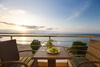 a table with wine glasses and a bowl of grapes at Neachora Beachfront Suites in Chania Town