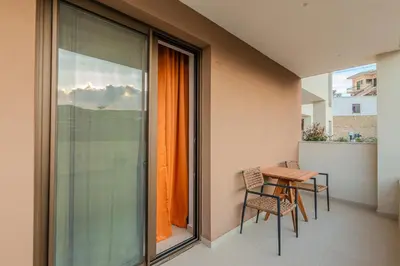 a balcony with a table and chairs and a window at Sarana Suites Crete in Kissamos
