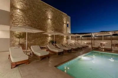 a swimming pool with lounge chairs and umbrellas at Sarana Suites Crete in Kissamos