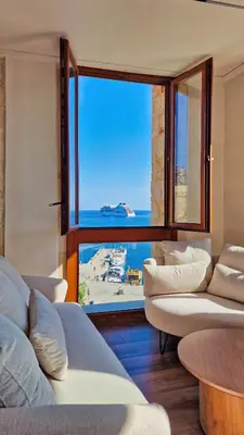 a living room with couches and a large window at Pallazzo Dei Miracoli - Luxe 3BR apt Sea & Old Port Terrace View in Chania Town