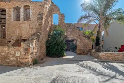an old stone building with a palm tree and a street at Pallazzo Dei Miracoli - Luxe 3BR apt Sea & Old Port Terrace View in Chania Town