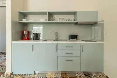 a kitchen with white cabinets and a sink at Altirina Studios in Almirida
