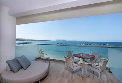a room with a table and chairs and a view of the ocean at EdgeWater Beach Hotel in Chania Town