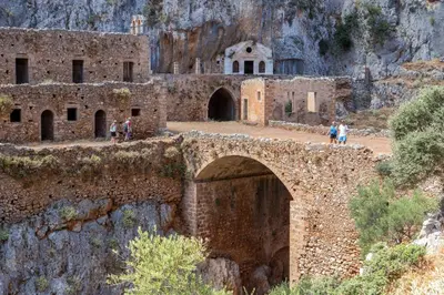 an old stone bridge with a building on a mountain at Cozy Light Nest Chania Crete in Kounoupidhianá