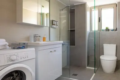 a bathroom with a washing machine and a shower at Cozy Light Nest Chania Crete in Kounoupidhianá