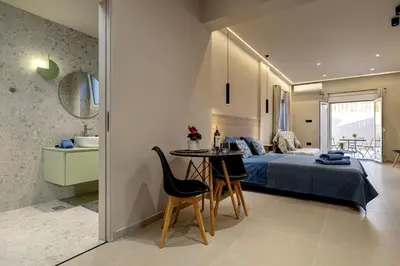 a bedroom with a bed and a table and chairs at Dom Azure Studios in Agia Marina Nea Kydonias