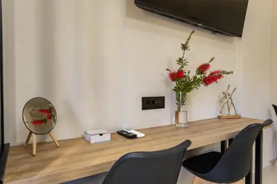 a table with a vase of flowers and a mirror at Dom Azure Studios in Agia Marina Nea Kydonias