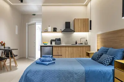 a bedroom with a blue bed and a kitchen at Dom Azure Studios in Agia Marina Nea Kydonias