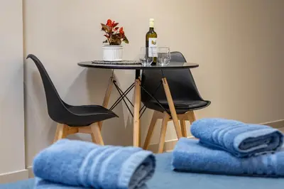 a table with a bottle of wine and a table with a chair at Dom Azure Studios in Agia Marina Nea Kydonias