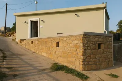 a building with a stone wall in front of it at Yalos Standard Studio - 5 mins to Elafonisi beach in Agios Padeleimon