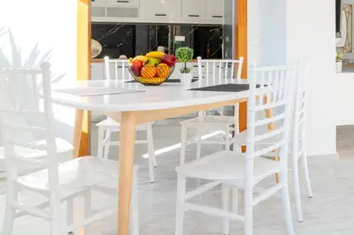 a white dining room table with white chairs and a bowl of fruit at Nafsika's Cozy Apartment in Chania Town