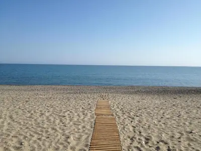 a wooden pathway through the sand on a beach at Lito Beach Hotel in Gerani Chanion