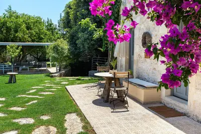 a table and chairs in a garden with purple flowers at Villa Athermigo in Gavalochori