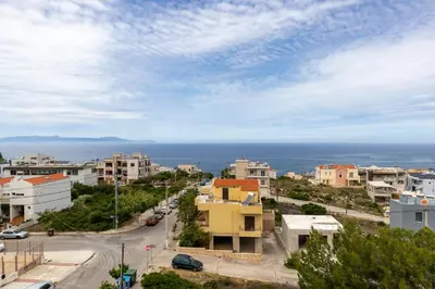 a city street with buildings and the ocean in the background at Maisonette in Koumpeli in Koumpeli
