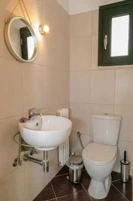 a bathroom with a sink and a toilet and a mirror at Maisonette in Koumpeli in Koumpeli