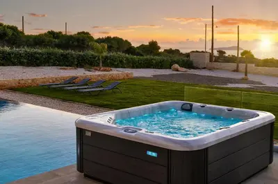 a hot tub sitting on a patio next to a pool at Luxurious Villas Rocca Blanco 1 & 2 in Kounoupidhianá