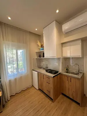 a kitchen with white cabinets and a sink and a window at EYTYXHS Studios in Palaiochóra
