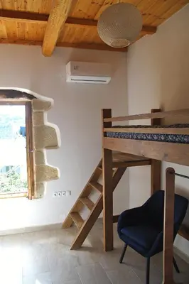 a room with a wooden table and a staircase and a window at The Village Hideaway - Traditional Stone House in Kissamos