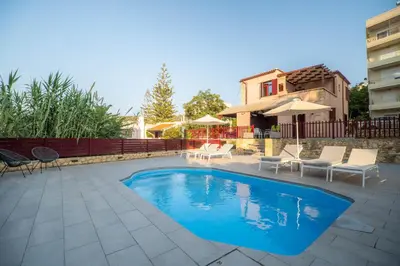 a swimming pool with chairs and a house at Casa Chris in Chania Town