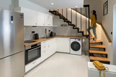 a woman in a kitchen with a washer and dryer at LOFTaki - Petite house next to Koum Kapi beach in Chania Town