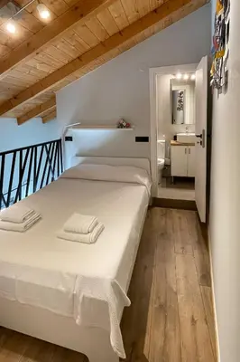 a bedroom with a white bed and a bathroom at LOFTaki - Petite house next to Koum Kapi beach in Chania Town